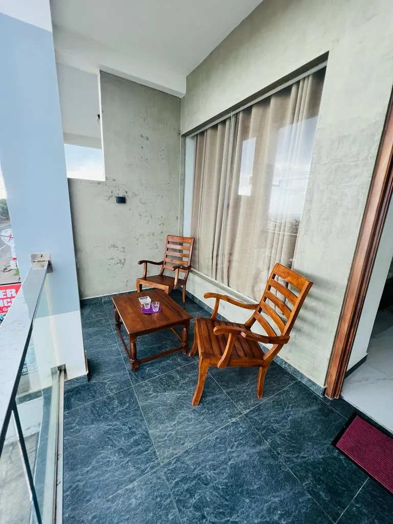 Covered balcony with wooden seating beside a room doorway
