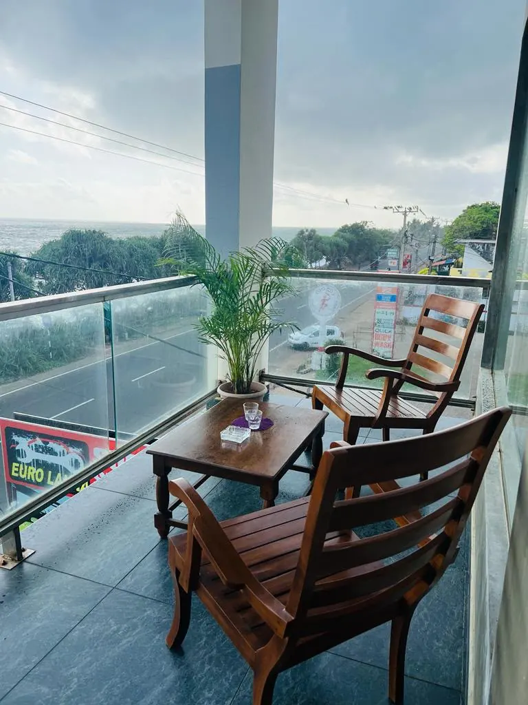 Balcony seating with a potted palm above the coast road