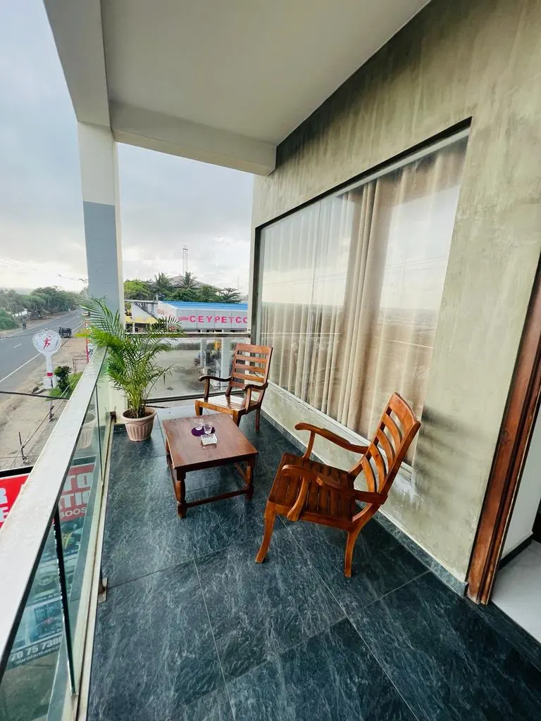 Glass railed balcony with wooden chairs and a low table