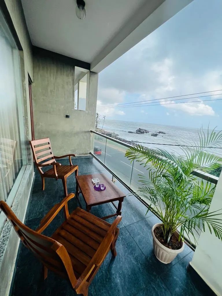 Balcony seating and a potted palm facing the open ocean