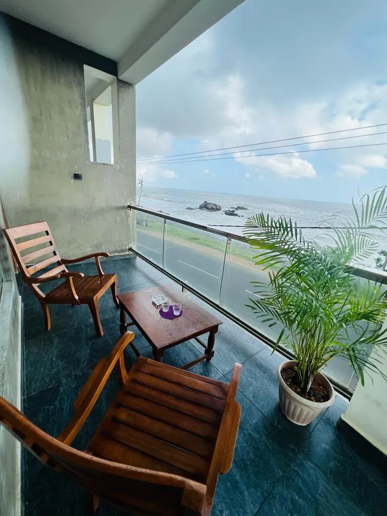 Ocean view balcony with wooden seating and a potted palm