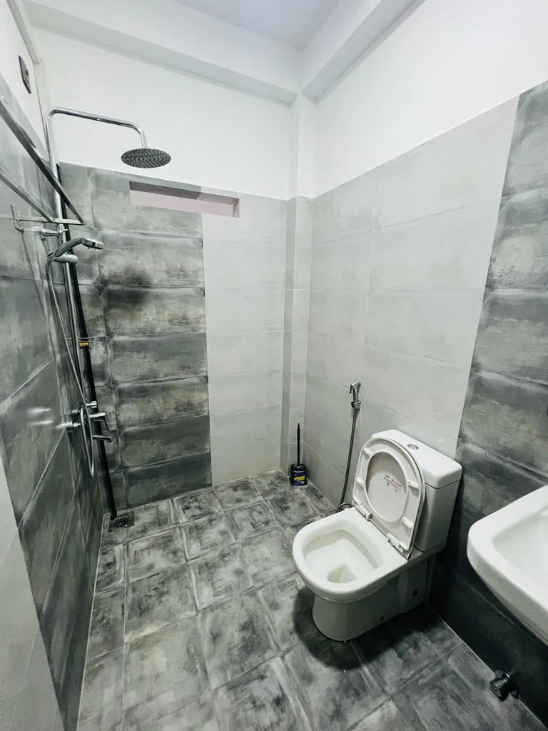 Tiled bathroom with a rain shower, toilet and wash basin