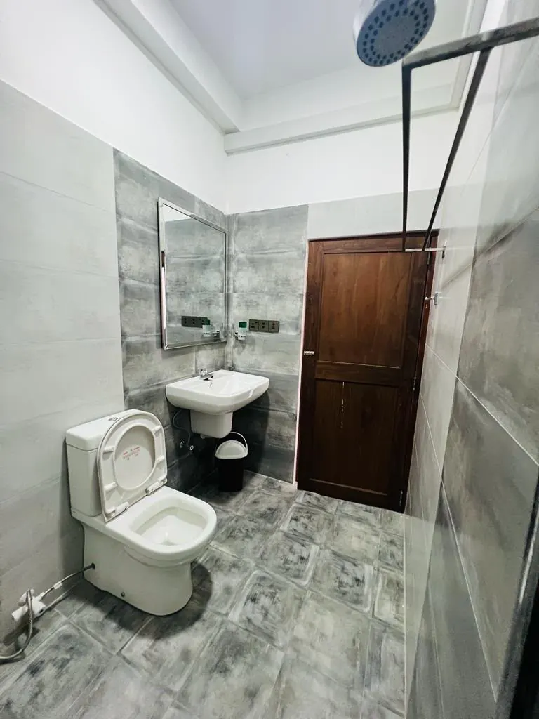 Bright tiled bathroom with a rain shower, toilet and wash basin