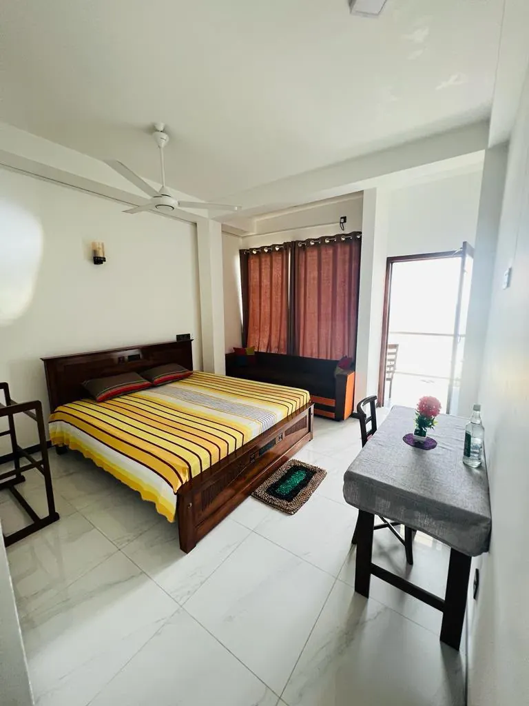 Bright double room with striped bedding and balcony access