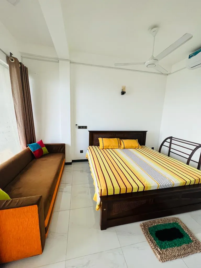 Air conditioned double room with a sofa and ceiling fan